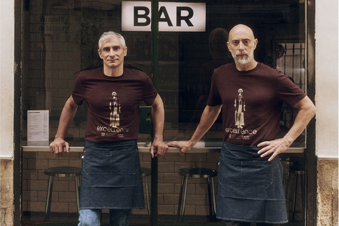 Cette photo montre deux personne devant leur bar portant des vêtement coresponsable personnalisés 